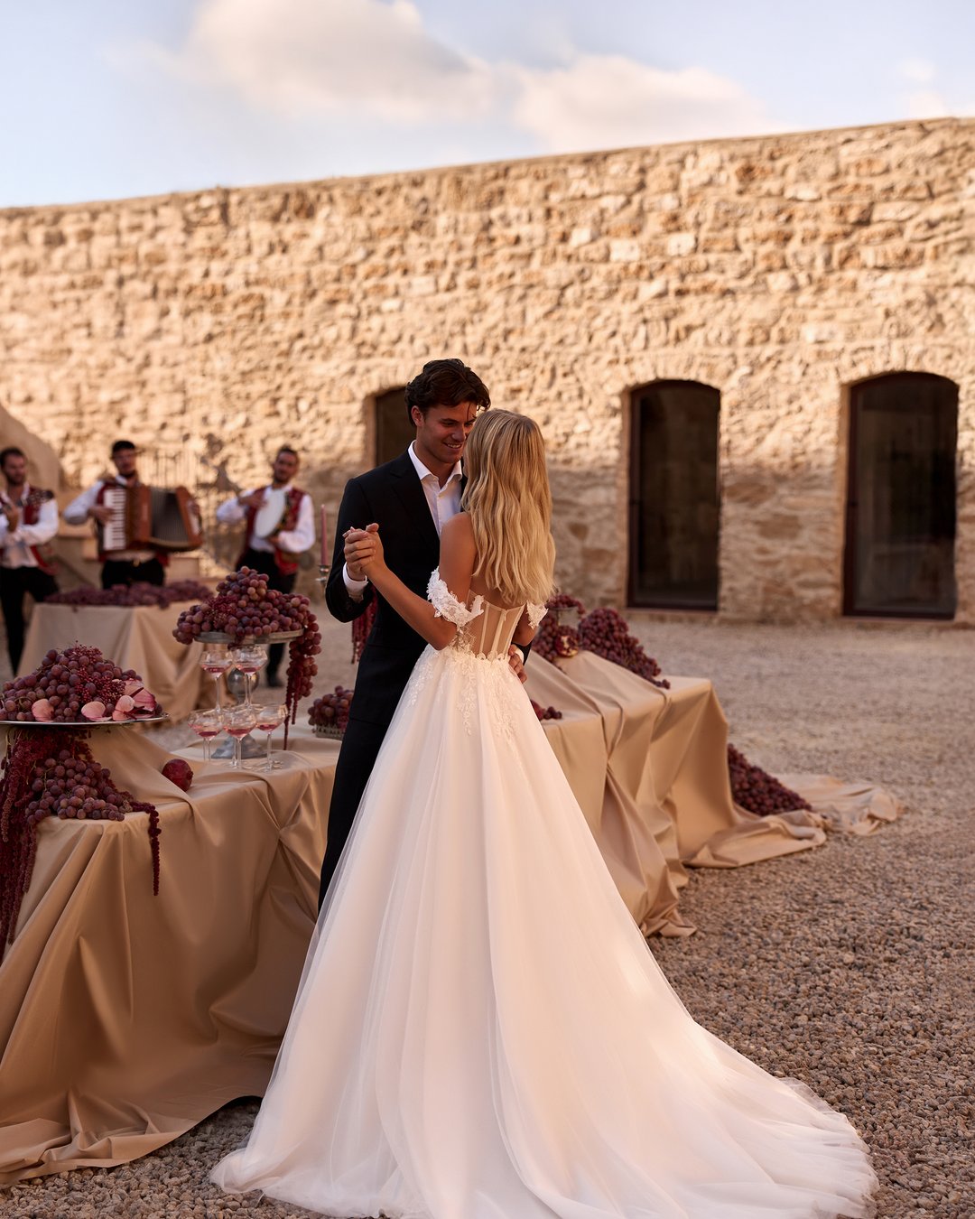 Suknia ślubna Horolina z kolekcji AnnaSposa to romantyczna propozycja dla przyszłych panien młodych pragnących połączyć elegancję z subtelnością. Wykonana z lekkiego tiulu i francuskiej koronki, zachwyca rozkloszowanym krojem, gorsetowym wykończeniem oraz delikatnymi opadającymi ramiączkami, które podkreślają sylwetkę. Efektowne kryształki oraz rozcięcie w stylu V dodają całości blasku, a długi tren wprowadza nutę spektakularności w tym niezapomnianym dniu.
