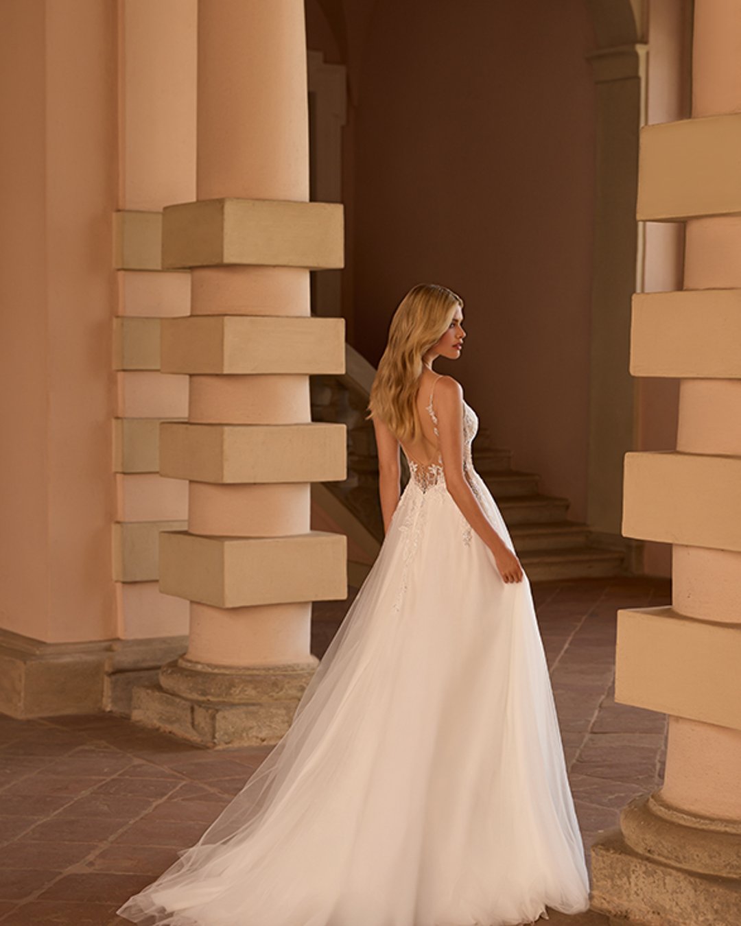 Model Setaria to delikatna i romantyczna suknia ślubna na cienkich ramiączkach, zachwycająca lekkością i kobiecym urokiem. Gorset z dekoltem w kształcie litery V oraz przezroczyste, błyszczące detale pięknie podkreślają sylwetkę, a szeroka, tiulowa spódnica w linii A nadaje kreacji zwiewności. Idealna propozycja dla Panny Młodej ceniącej klasyczną elegancję z nutą nowoczesności.