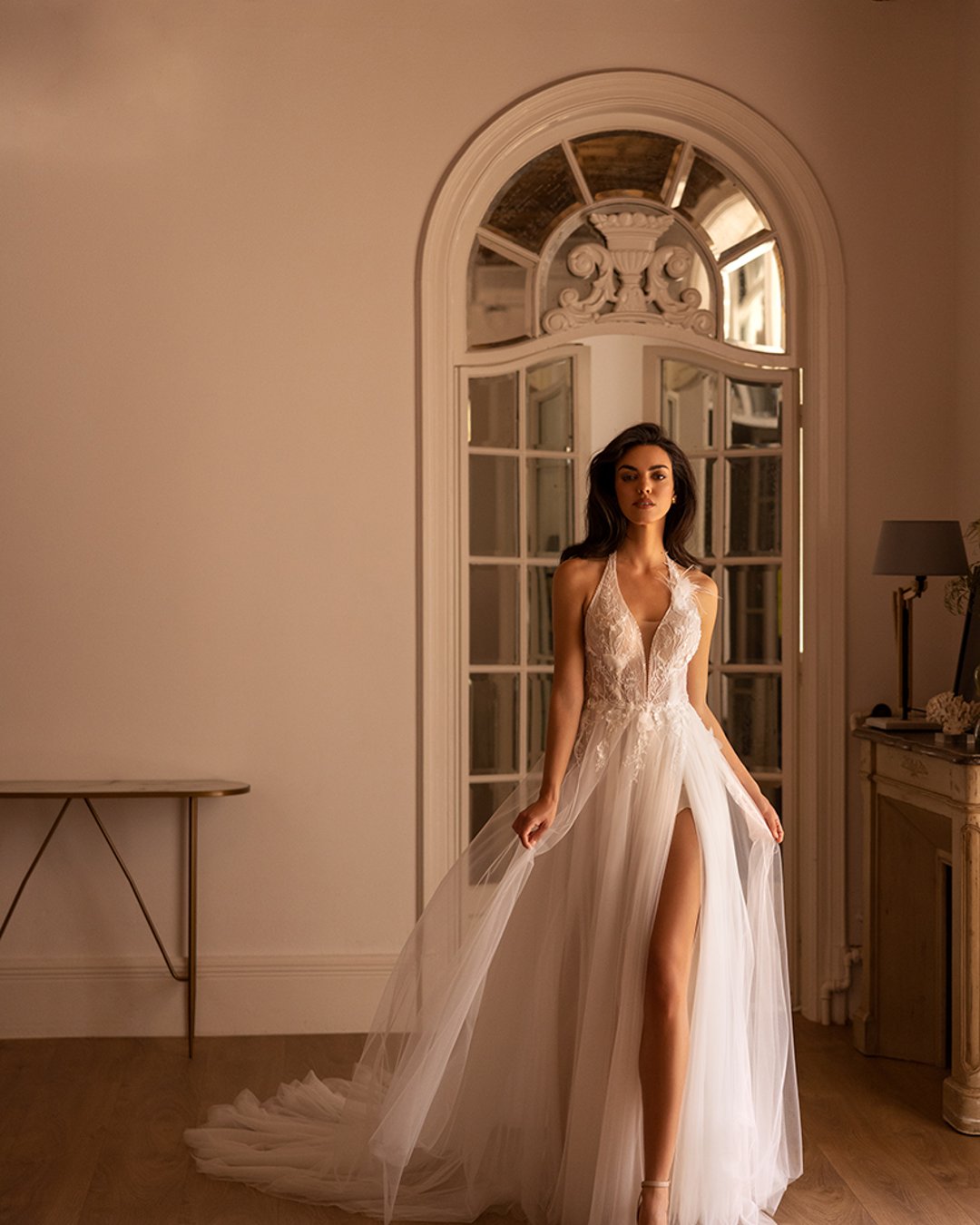 Suknia Elizabeth Passion o linii A z głębokim dekoltem, koronkowymi detalami, piórami oraz efektownym rozcięciem na nogę. Z tyłu zapinana na szyję, idealnie podkreślająca sylwetkę.