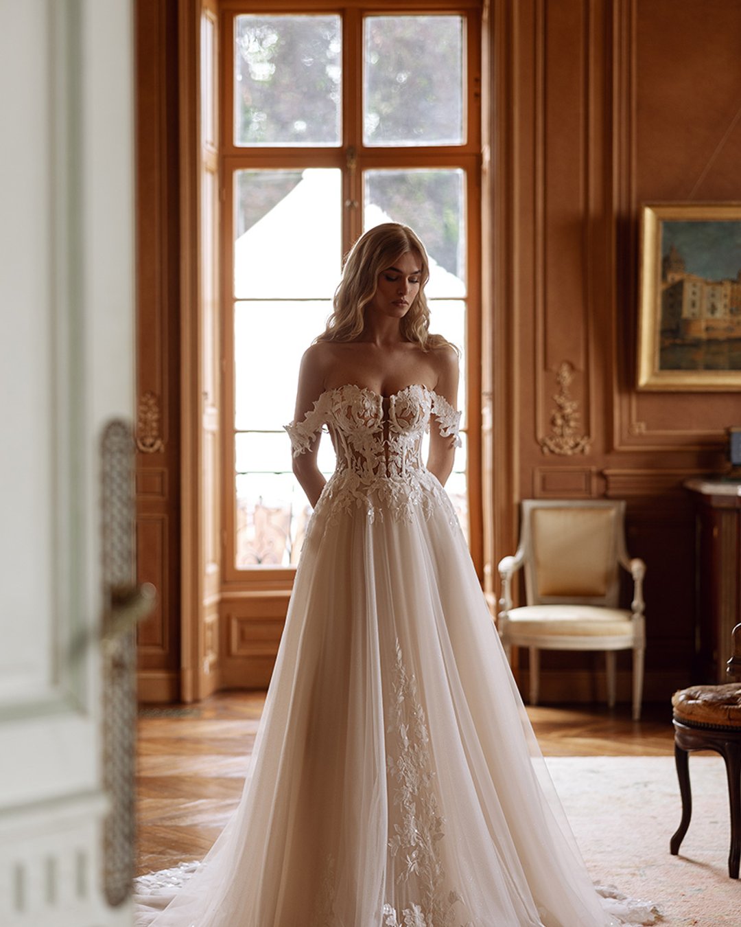 Bautista to delikatna i lekka tiulowa kreacja o kroju princesski. Gorsetowy fason podkreśla sylwetkę, a zdobienia w postaci małych kwiatków 3D dodają romantycznego charakteru. Długi tren pięknie układa się podczas ruchu, podkreślając wyjątkowość kreacji. Idealna dla panny młodej, która pragnie wyglądać lekko i elegancko.