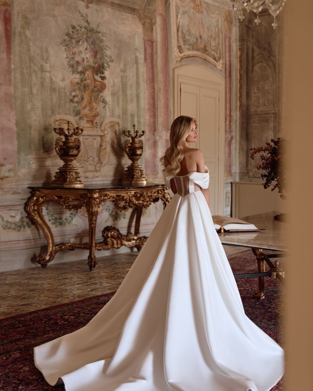 Suknia Toya to wyjątkowa propozycja od Anna Sposa dla miłośniczek klasycznej elegancji. Gładka, wykonana z luksusowej satyny, posiada gorsetowy fason z opadającymi ramiączkami i transparentnymi wstawkami, które dodają subtelnej zmysłowości. Całość uzupełniają błyszczące kryształki, przezroczyste plecy oraz efektowny rozporek.