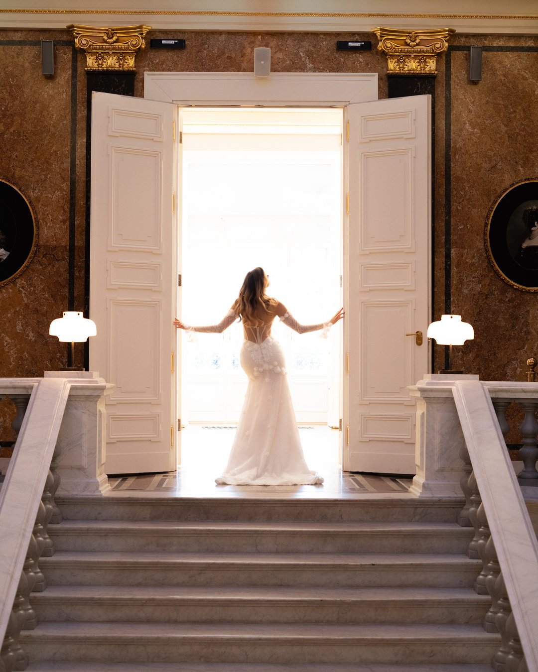 Suknia ślubna Charlotte z kolekcji LaLiven to prawdziwa ucieleśnienie elegancji i nowoczesnego romantyzmu. Jej koronkowy gorset z efektownym pasem w kształcie litery V oraz nakładane rękawy doskonale podkreślają sylwetkę, a błyszczące detale i kwiatowe motywy dodają subtelnej finezji. Model w stylu syrenki, idealnie dopasowany, sprawi, że każda panna młoda poczuje się wyjątkowo w swoim wielkim dniu.