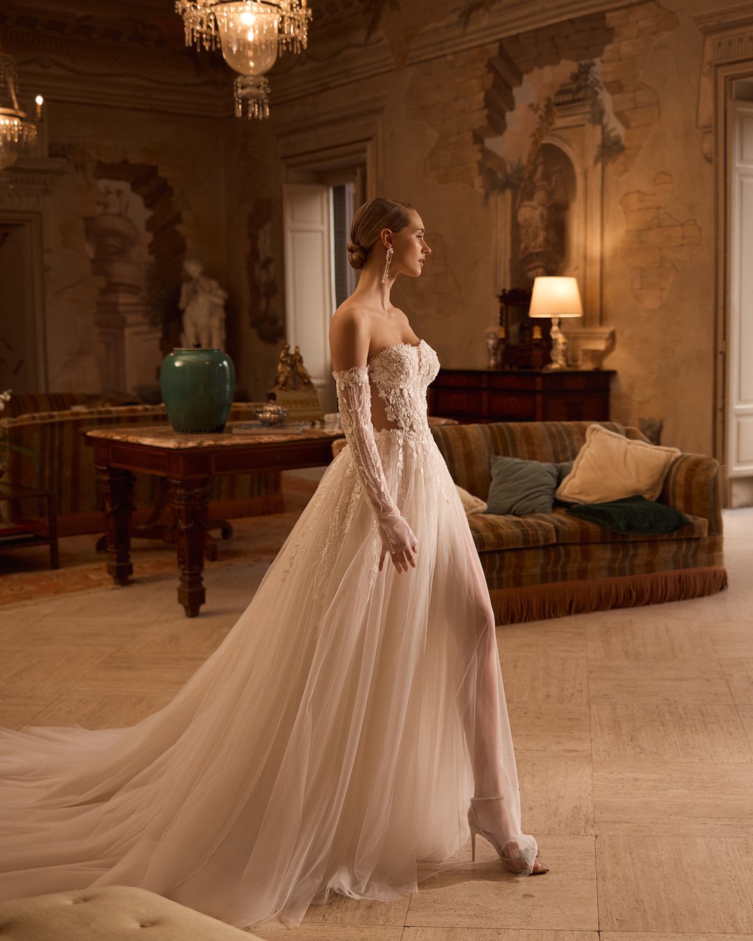 Suknia ślubna 5831 z kolekcji Elizabeth Passion łączy nowoczesny design z romantycznym wyrafinowaniem. Przezroczysta góra ozdobiona delikatną koronką i kwiatowymi aplikacjami, w połączeniu z szeroką, tiulową spódnicą, tworzy niepowtarzalny efekt, który zachwyca blaskiem. Nakładane rękawy dodają całości subtelności, sprawiając, że każda panna młoda poczuje się jak prawdziwa królewna w tym wyjątkowym dniu.