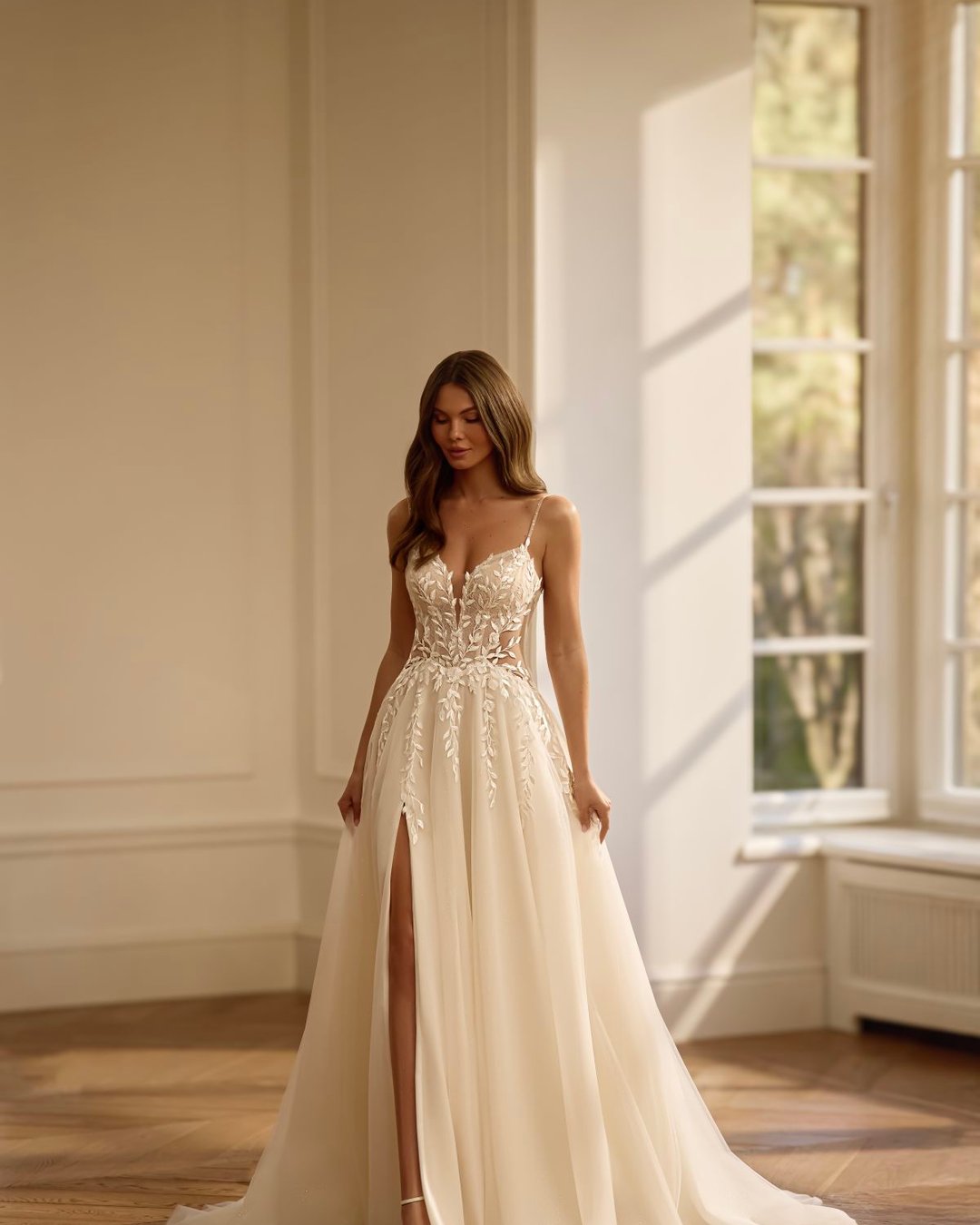 Suknia wykonana z tiulu na cienkich ramiączkach z wyciętymi, przezroczystymi bokami, które pięknie modelują sylwetkę.
Gorset zdobiony koronką w kształcie listków, głęboki dekolt w kształcie litery V oraz efektownie wycięte plecy na cienkich, ozdobnych ramiączkach.
Szeroka, lekka spódnica z rozcięciem na nodze dodaje subtelnego seksapilu.
Przezroczysta góra, lekki tiulowy tren.