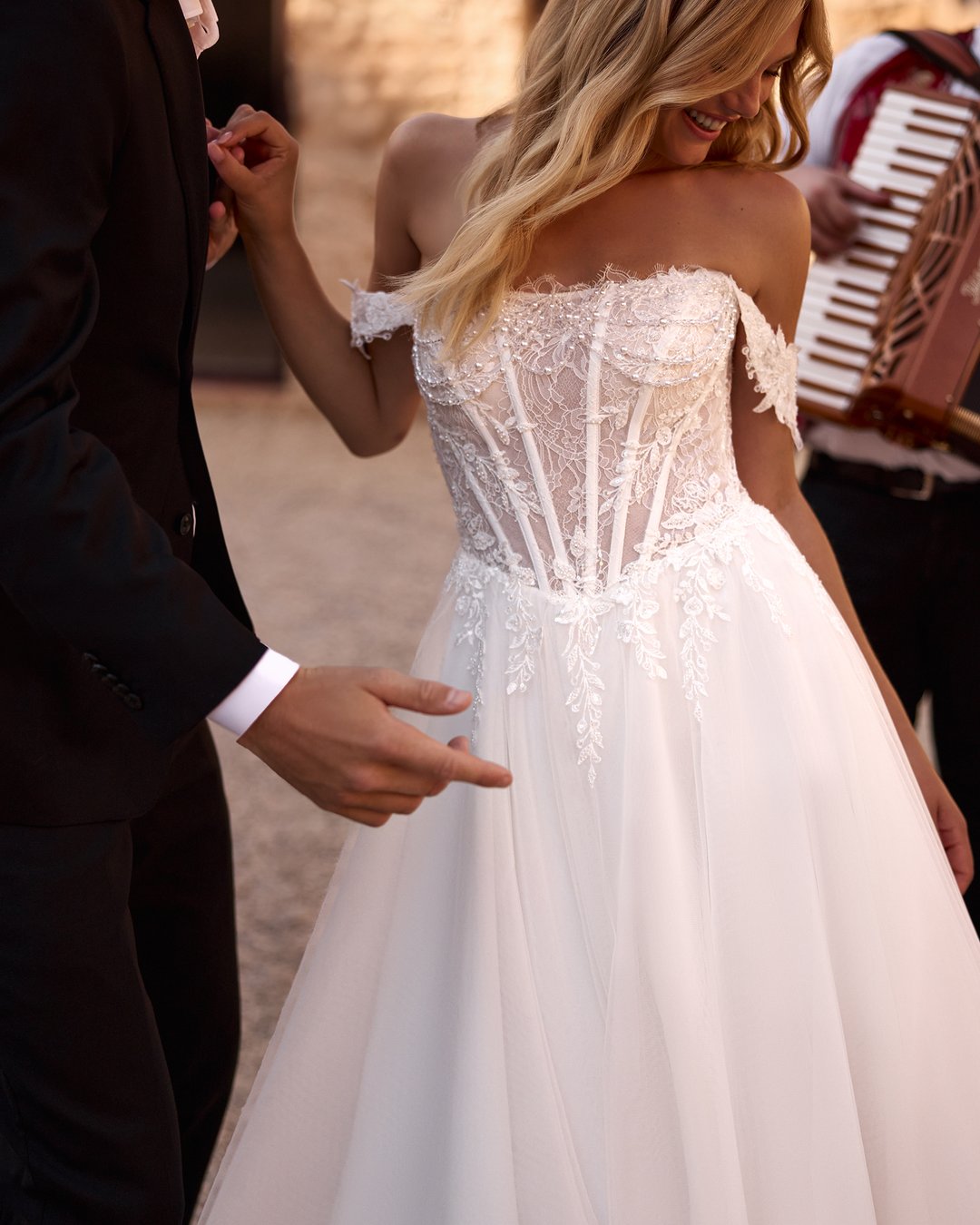 Suknia ślubna Horolina z kolekcji AnnaSposa to romantyczna propozycja dla przyszłych panien młodych pragnących połączyć elegancję z subtelnością. Wykonana z lekkiego tiulu i francuskiej koronki, zachwyca rozkloszowanym krojem, gorsetowym wykończeniem oraz delikatnymi opadającymi ramiączkami, które podkreślają sylwetkę. Efektowne kryształki oraz rozcięcie w stylu V dodają całości blasku, a długi tren wprowadza nutę spektakularności w tym niezapomnianym dniu.