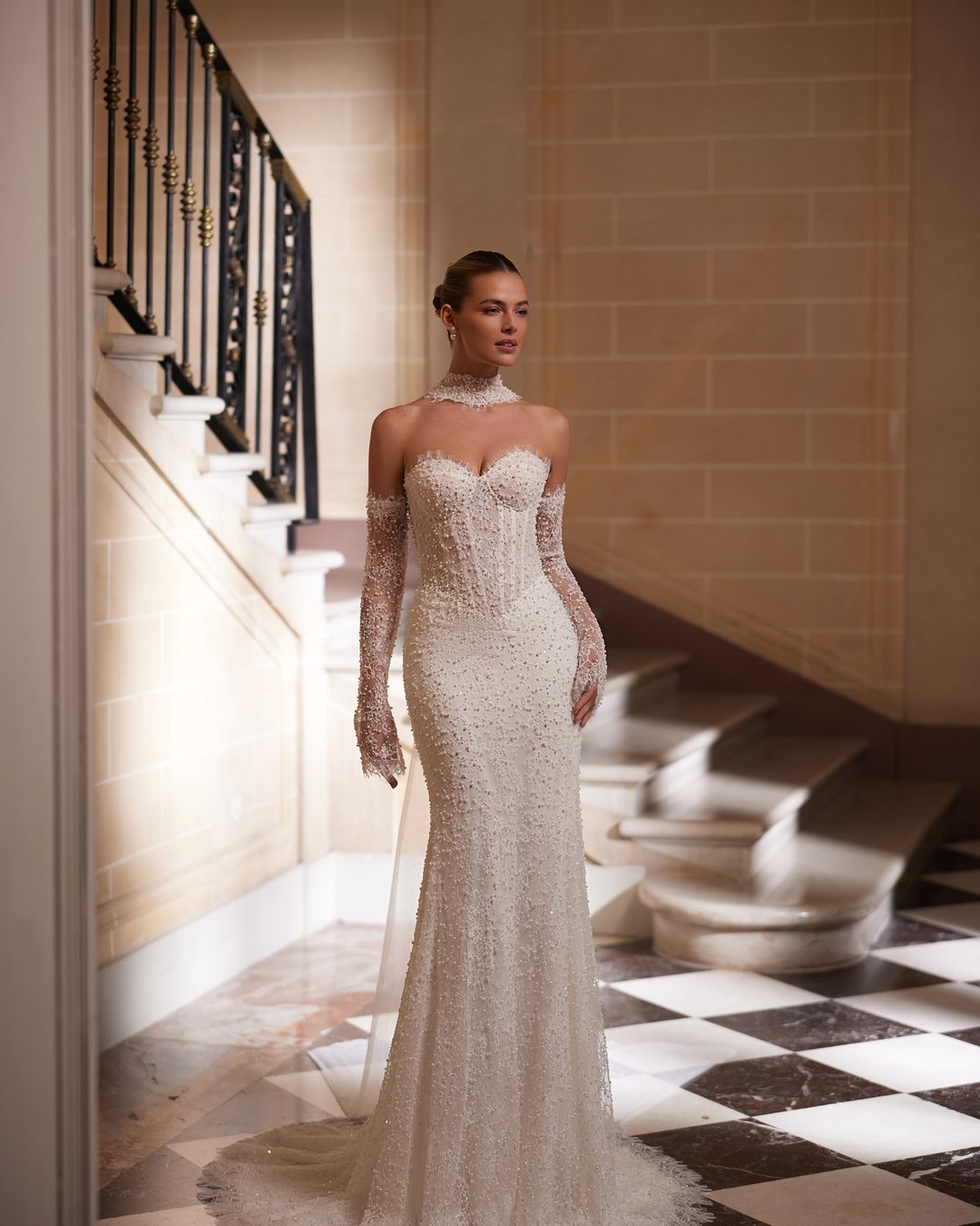 Suknia ślubna Amity z kolekcji AnnaSposa to kwintesencja elegancji i nowoczesności, która zachwyca dopasowanym krojem syrenki oraz zjawiskowym trenem. Wykonana z francuskiej koronki ozdobionej perłami, podkreśla kobiece kształty dzięki gorsetowemu fasonowi i efektownemu pasowi w kształcie litery V. Dodatkowy urok sukni nadaje wyjątkowy choker, który dopełnia całość, czyniąc każdą pannę młodą prawdziwą królową w dniu jej ślubu.