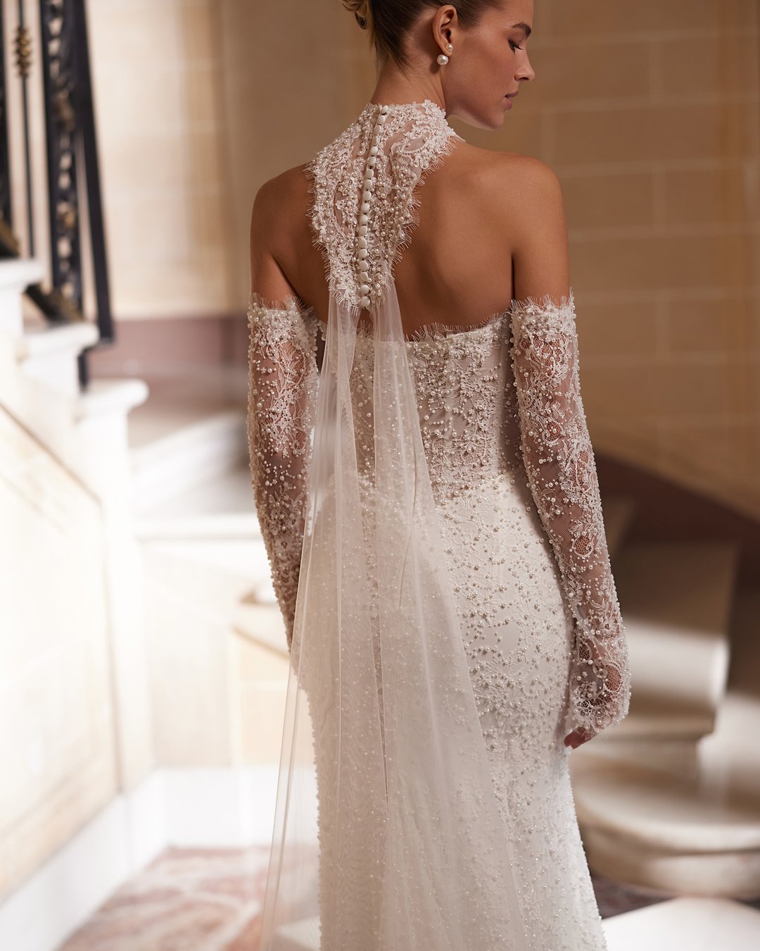 Suknia ślubna Amity z kolekcji AnnaSposa to kwintesencja elegancji i nowoczesności, która zachwyca dopasowanym krojem syrenki oraz zjawiskowym trenem. Wykonana z francuskiej koronki ozdobionej perłami, podkreśla kobiece kształty dzięki gorsetowemu fasonowi i efektownemu pasowi w kształcie litery V. Dodatkowy urok sukni nadaje wyjątkowy choker, który dopełnia całość, czyniąc każdą pannę młodą prawdziwą królową w dniu jej ślubu.