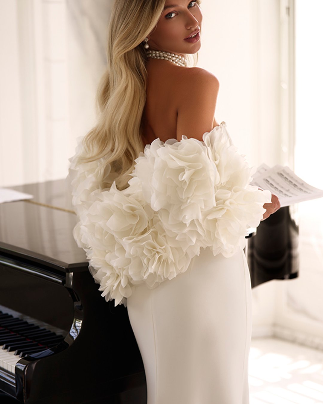 Suknia Uliana od Anna Sposa to esencja współczesnej elegancji z nutą klasyki. Gładka, dopasowana linia z wyraźnym pasem w literę V i gorsetowym topem pięknie podkreśla sylwetkę. Subtelne perełki przy dekolcie oraz spektakularne bolerko z kwiatowymi aplikacjami dodają szyku i oryginalności. To propozycja dla panny młodej, która ceni sobie minimalizm, ale nie boi się wyrazistych detali.