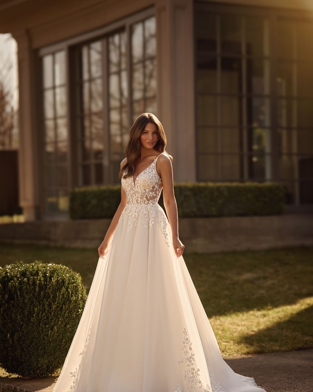 Suknia Obsidian to klasyczna i delikatna suknia ślubna o linii A, wykonana z tiulu ozdobionego subtelną koronką w kształcie drobnych kwiatków. Gorset z głębokim dekoltem w kształcie litery V oraz transparentnymi plecami nadaje sylwetce lekkości i romantyzmu. Suknia oparta na cienkich ramiączkach zdobionych perełkami pięknie eksponuje ramiona i szyję. Całość wieńczy lekki, delikatny tren, który płynnie dopełnia elegancki charakter sukni.