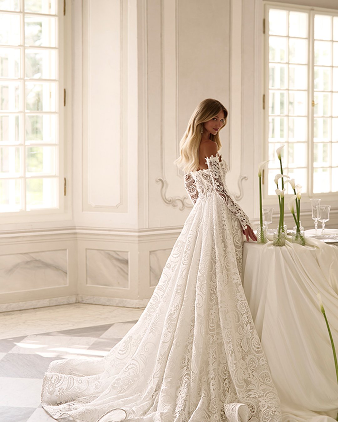 Suknia ślubna Bohnia od Anna Sposa to elegancka princeska z szeroką spódnicą i transparentnym gorsetem. Wykonana z bogato zdobionej gipiury, ozdobiona perłami, z prostym dekoltem i odpinanymi rękawami. Idealna dla panny młodej marzącej o bajkowym wyglądzie.