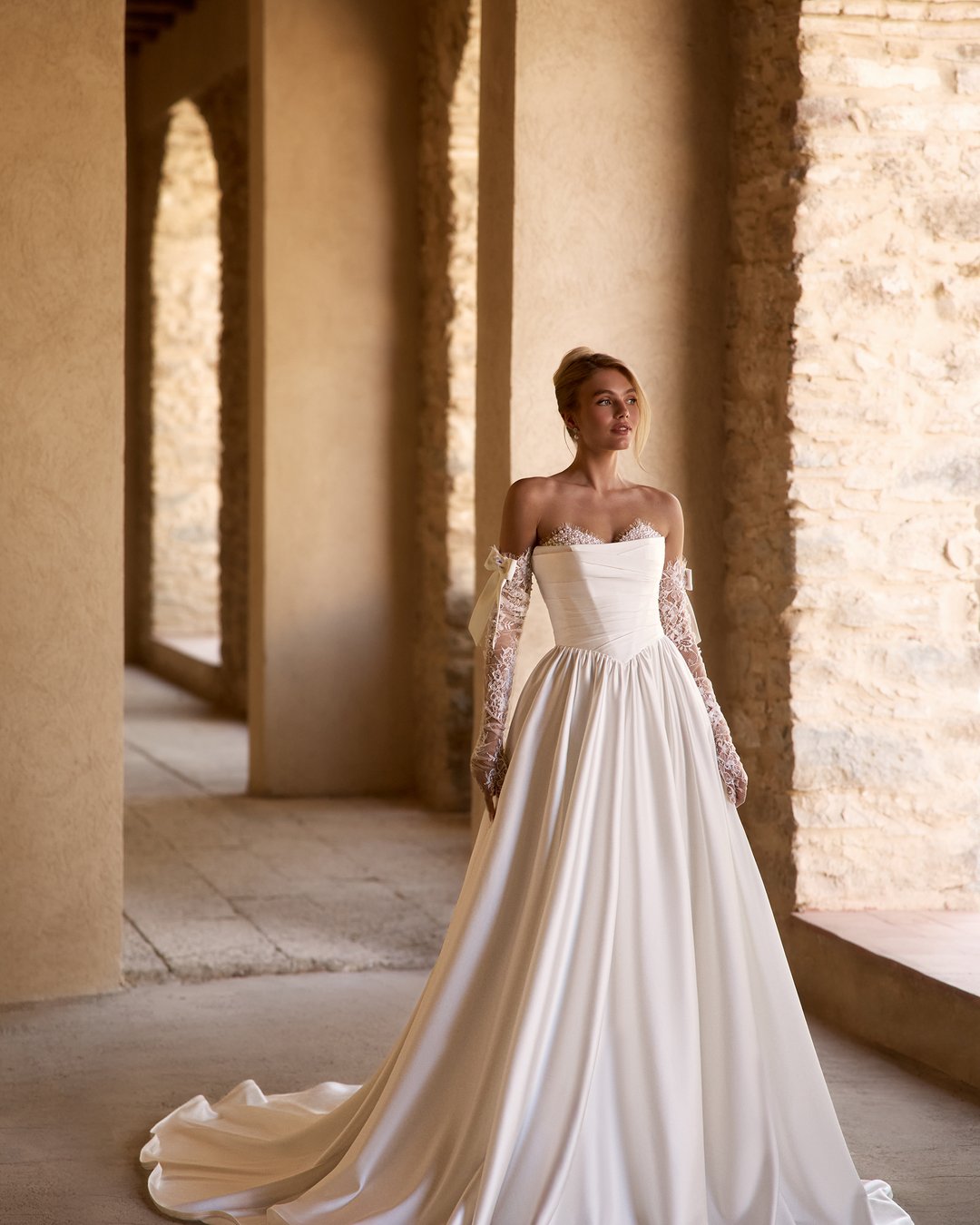 Suknia ślubna Frantelia z kolekcji AnnaSposa to kwintesencja klasycznej elegancji, która zachwyca zarówno gorsetowym krojem, jak i rozkloszowanym dołem, idealnie podkreślającym sylwetkę. Dekolt w kształcie serca oraz subtelne perły dodają jej niepowtarzalnego blasku, a tren nadaje całości romantycznego charakteru. Wybierz Frantelię, aby w dniu swojego ślubu poczuć się jak prawdziwa księżniczka.