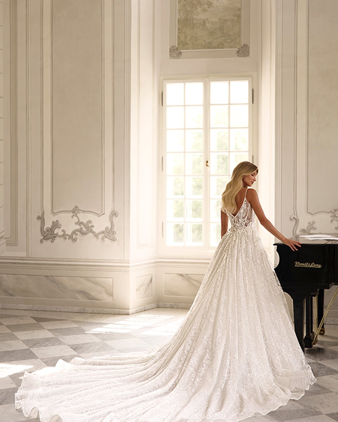 Suknia ślubna Kupelius to olśniewająca princessa z szeroką, błyszczącą spódnicą, zdobiona perełkami i koronką. Na cienkich ramiączkach, z prostym dekoltem i delikatnie prześwitującą górą – elegancja w najczystszej formie.