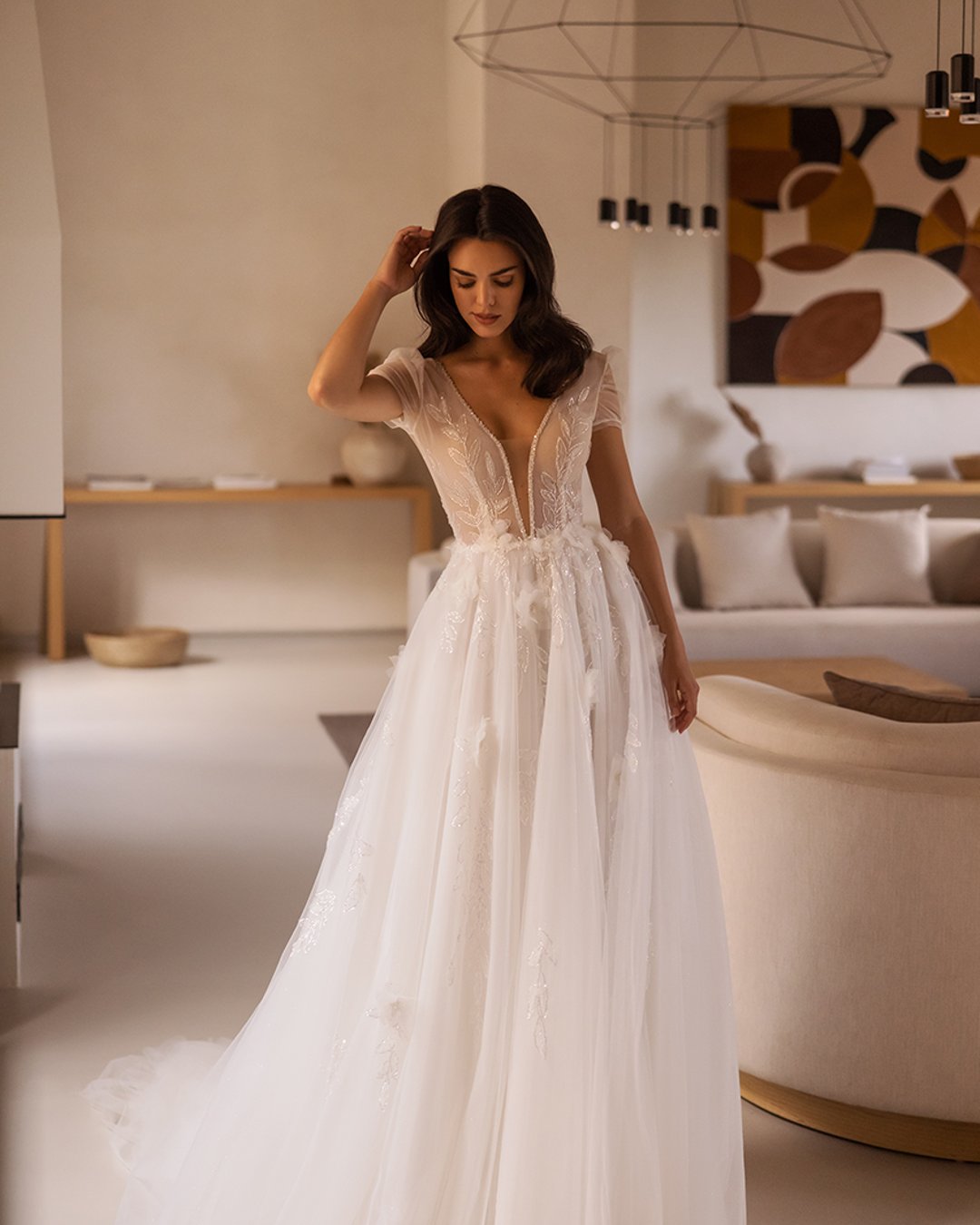 Delikatna suknia o linii A z koronkowym gorsetem ozdobionym kwiatowymi aplikacjami, krótkimi rękawkami z tiulu i lekką spódnicą, idealna na romantyczny ślub.