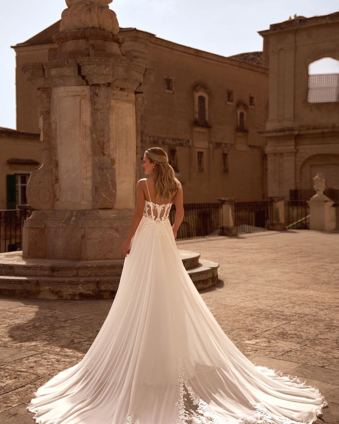 Model Bogdana to romantyczna suknia ślubna o kroju A-line, wykonana z niezwykle lekkiego i zwiewnego muślinu, który pięknie układa się w ruchu. Jej delikatność idzie w parze z elegancją i kobiecością, tworząc stylizację idealną zarówno na ślub w plenerze, jak i elegancką uroczystość w pałacowym stylu.