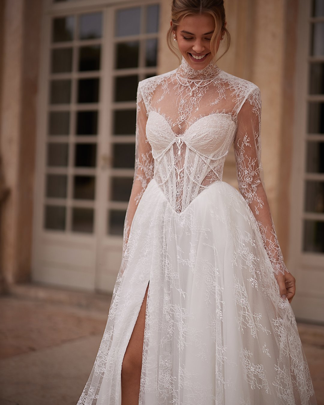 Suknia Kaviella z kolekcji AnnaSposa to połączenie elegancji i nowoczesności, które zachwyci każdą pannę młodą. Wykonana z delikatnej francuskiej koronki, z zmysłowym rozporkiem i gorsetowym krojem, subtelnie podkreśla sylwetkę, a przezroczyste szerokie ramiączka dodają jej lekkości. Uzupełniona o bolerko i efektowny tren, ta suknia sprawi, że poczujesz się wyjątkowo w najważniejszym dniu swojego życia.