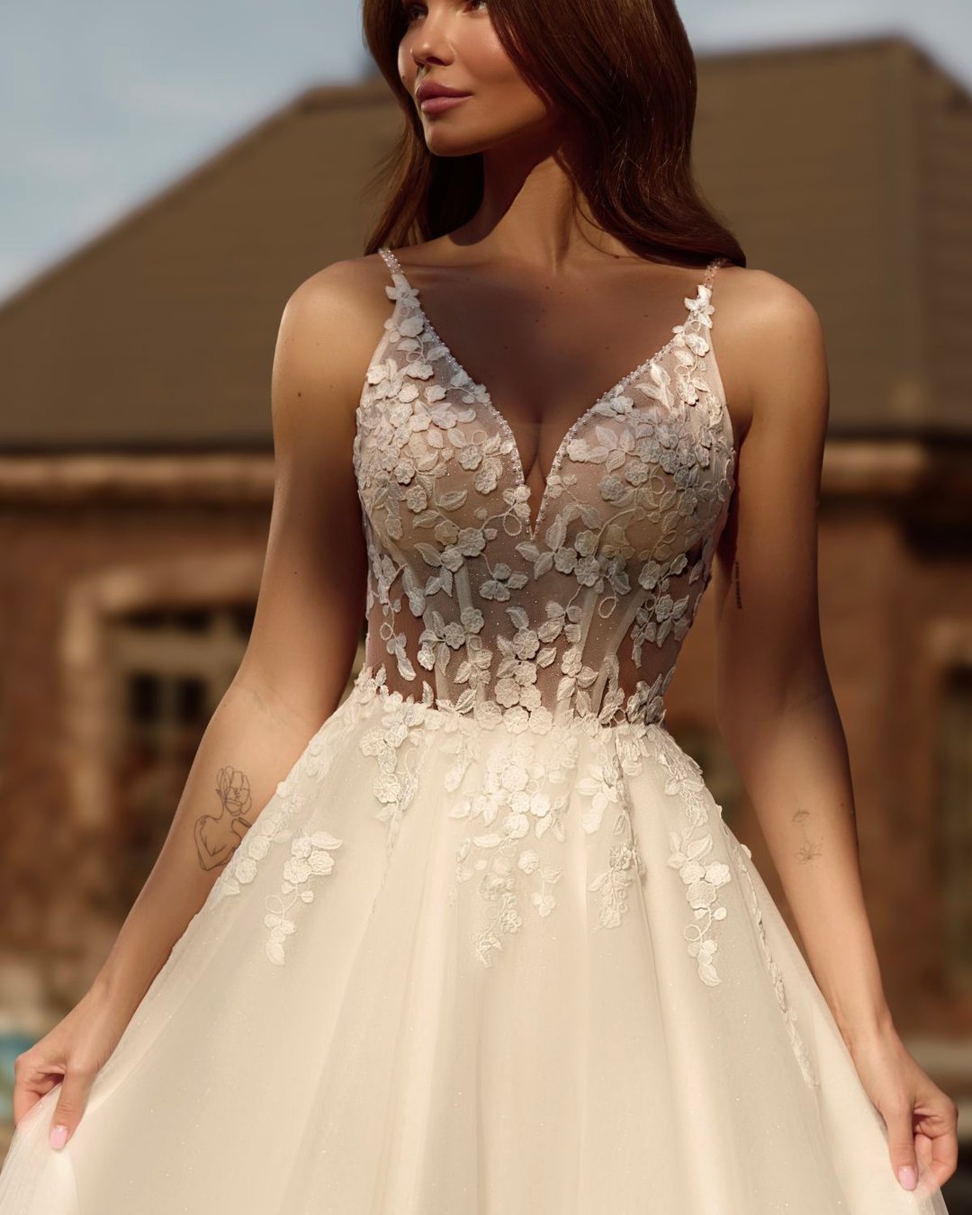 Suknia Obsidian to klasyczna i delikatna suknia ślubna o linii A, wykonana z tiulu ozdobionego subtelną koronką w kształcie drobnych kwiatków. Gorset z głębokim dekoltem w kształcie litery V oraz transparentnymi plecami nadaje sylwetce lekkości i romantyzmu. Suknia oparta na cienkich ramiączkach zdobionych perełkami pięknie eksponuje ramiona i szyję. Całość wieńczy lekki, delikatny tren, który płynnie dopełnia elegancki charakter sukni.