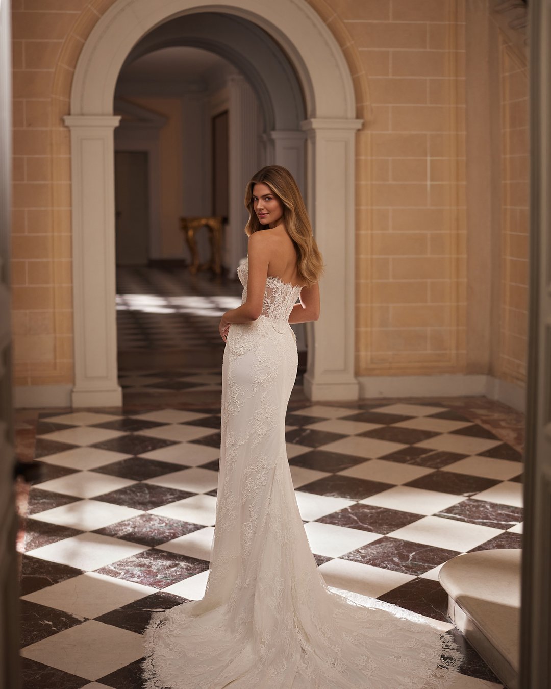 Suknia ślubna Vestira z kolekcji AnnaSposa to kwintesencja elegancji i klasyki, łącząca w sobie dwuczęściowy design z zjawiskowym trenem. Wykonana z delikatnego tiulu i francuskiej koronkowej tkaniny, ozdobiona perłami oraz przezroczystymi nakładanymi rękawami, podkreśla kobiece kształty dzięki gorsetowemu fasonowi i baskince. Idealna dla panien młodych pragnących olśniewać w dniu swojego ślubu.