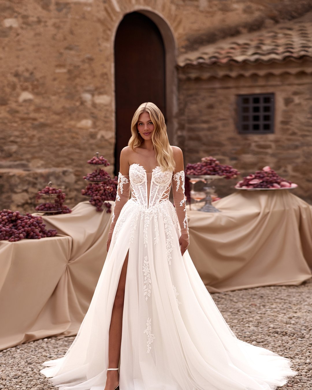 Suknia Rouwen z kolekcji AnnaSposa to kwintesencja romantyzmu i elegancji, łącząca w sobie lekki tiul z efektownym gorsetem i rozkloszowanym dołem. Delikatne, przezroczyste nakładane rękawy oraz subtelny rozporek dodają całości zmysłowości, podkreślając sylwetkę w pasie. Ta wyjątkowa kreacja sprawi, że każda panna młoda poczuje się jak prawdziwa księżniczka w dniu swojego ślubu.