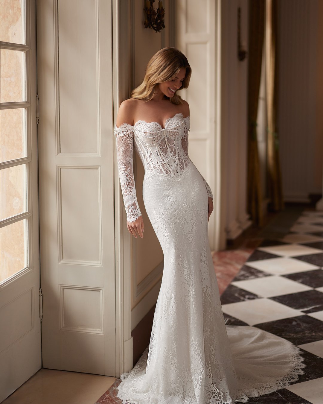 Suknia ślubna Sparkle z kolekcji AnnaSposa to ucieleśnienie nowoczesnej elegancji, łączące w sobie romantyzm długich rękawów i efektowny tren. Jej dopasowany krój w stylu tuby, ozdobiony francuską koronką i delikatnymi perłami, podkreśla sylwetkę, a przezroczysty gorset dodaje wyjątkowego szyku. Idealna dla panien młodych, które pragną w dniu swojego ślubu emanować blaskiem i pewnością siebie.