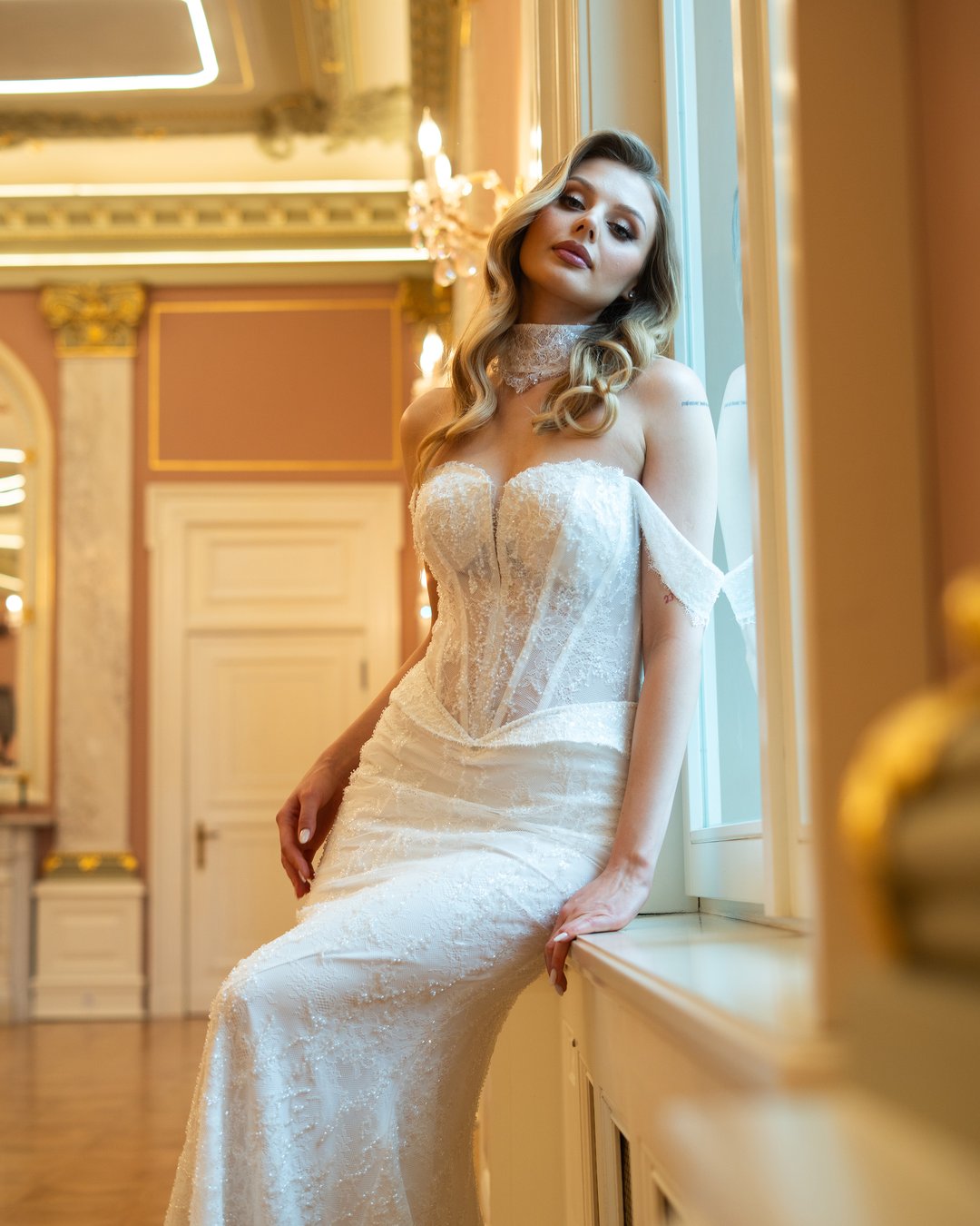Suknia ślubna Bianca z kolekcji LaLiven to doskonałe połączenie klasyki i nowoczesności, które zachwyca swoją elegancją. Dwuczęściowa konstrukcja w kształcie tuby, ozdobiona francuską koronką i subtelnym trenem, podkreśla sylwetkę, a efektowne nakładane rękawki oraz choker dodają jej wyjątkowego charakteru. Dzięki wąskiej baskince i lśniącemu wykończeniu, Bianca sprawi, że każda panna młoda poczuje się jak prawdziwa gwiazda w dniu swojego ślubu.