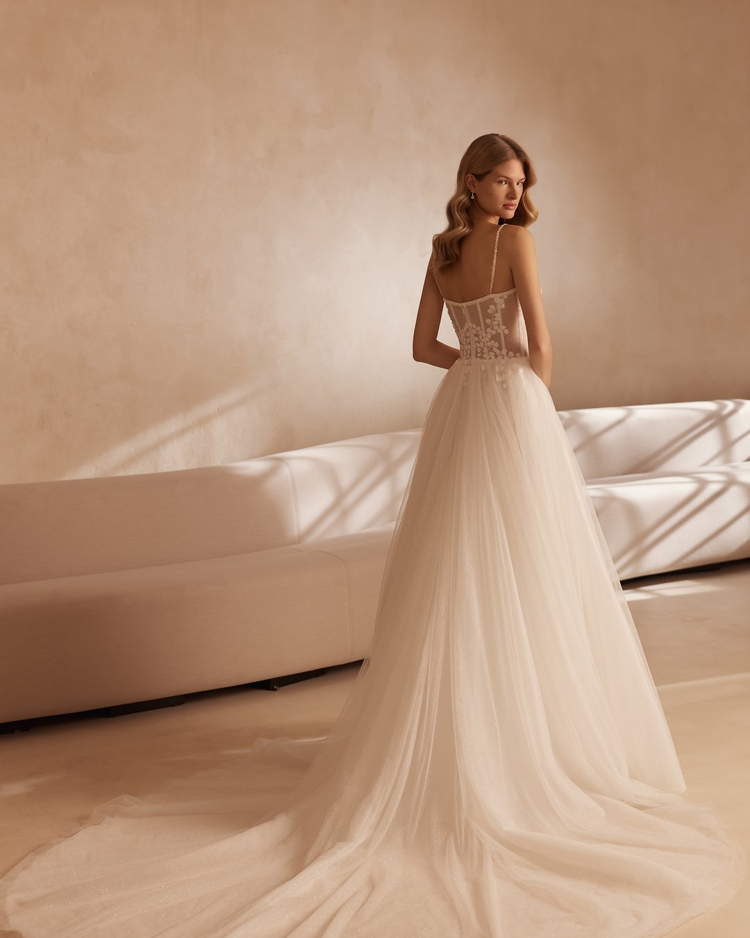 Suknia ślubna 5883 z kolekcji Elizabeth Passion emanuje romantyzmem i delikatnością, idealnie wpisując się w styl princessy. Jej szeroka spódnica z tiulu oraz gorset z koronkowymi detalami, ozdobiony subtelnymi kwiatkami, podkreślają kobiecą sylwetkę, a ramiączka dodają lekkości i elegancji. To wybór dla przyszłych panien młodych, które pragną poczuć się jak prawdziwe królowe w dniu swojego ślubu.