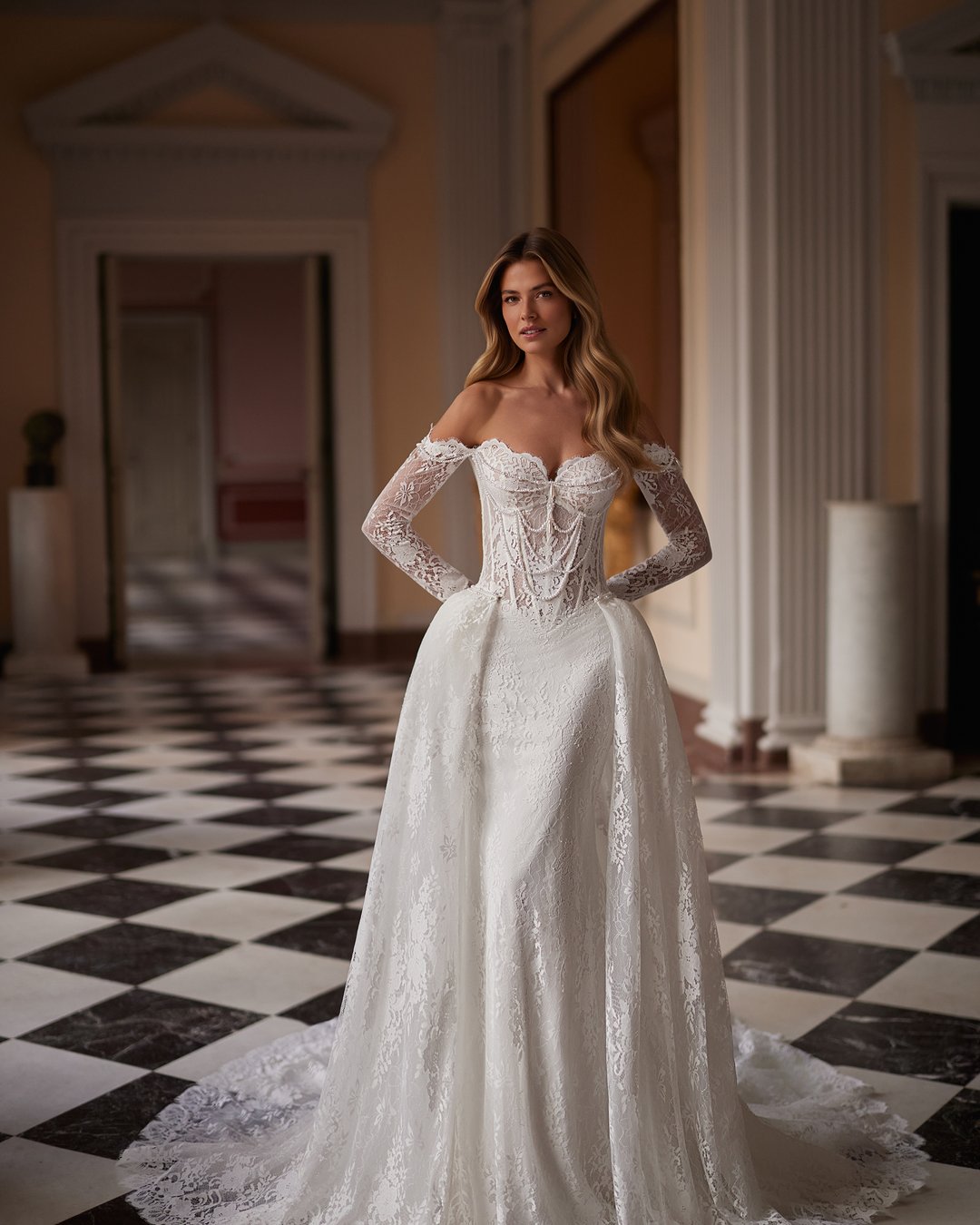 Suknia ślubna Sparkle z kolekcji AnnaSposa to ucieleśnienie nowoczesnej elegancji, łączące w sobie romantyzm długich rękawów i efektowny tren. Jej dopasowany krój w stylu tuby, ozdobiony francuską koronką i delikatnymi perłami, podkreśla sylwetkę, a przezroczysty gorset dodaje wyjątkowego szyku. Idealna dla panien młodych, które pragną w dniu swojego ślubu emanować blaskiem i pewnością siebie.