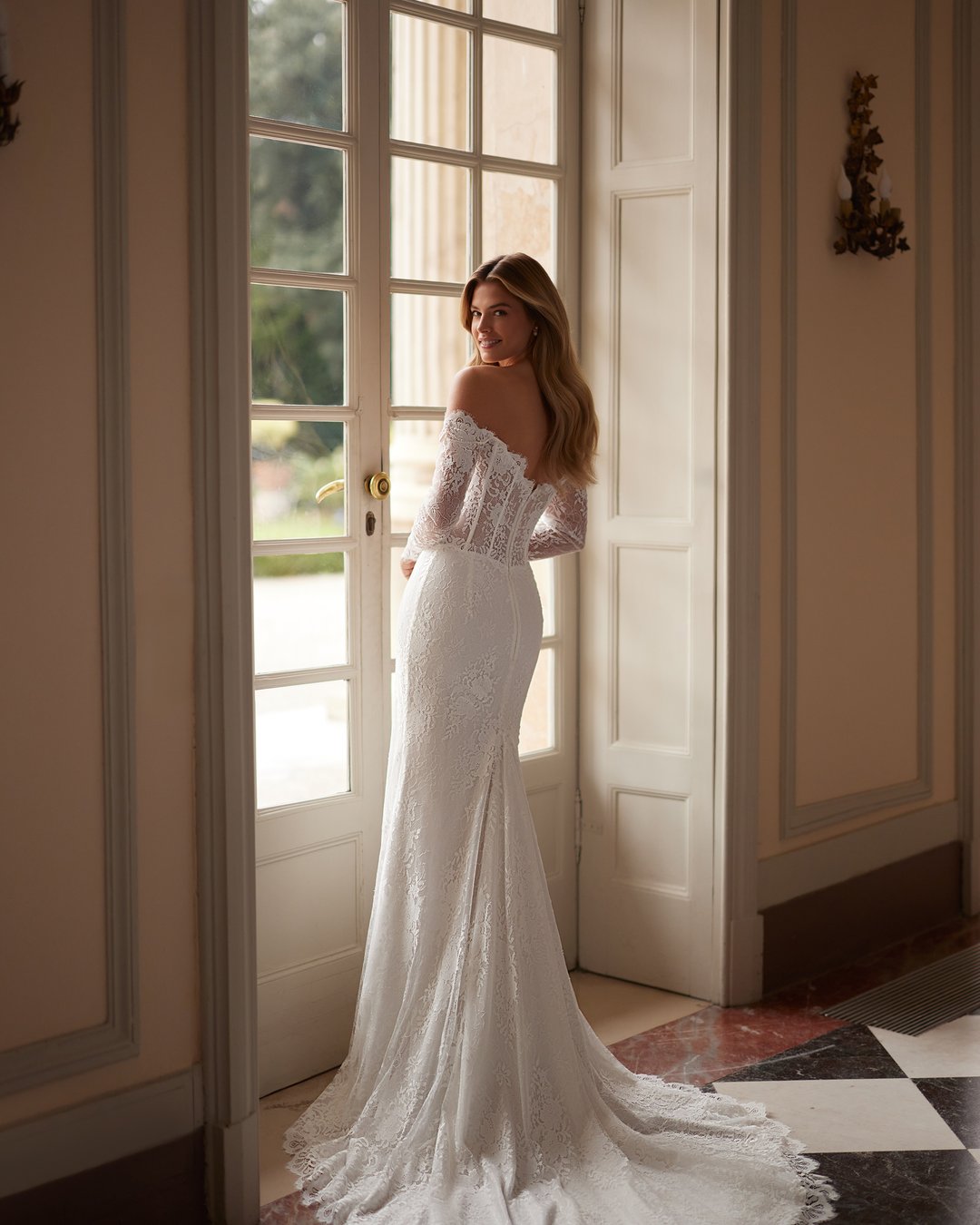 Suknia ślubna Sparkle z kolekcji AnnaSposa to ucieleśnienie nowoczesnej elegancji, łączące w sobie romantyzm długich rękawów i efektowny tren. Jej dopasowany krój w stylu tuby, ozdobiony francuską koronką i delikatnymi perłami, podkreśla sylwetkę, a przezroczysty gorset dodaje wyjątkowego szyku. Idealna dla panien młodych, które pragną w dniu swojego ślubu emanować blaskiem i pewnością siebie.