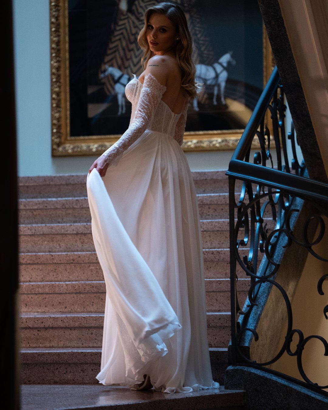 Suknia ślubna Viktoria z kolekcji LaLiven to kwintesencja boho elegancji, łącząca w sobie lekkość muslinu i subtelność francuskiej koronki. Dwuczęściowy fason z długimi rękawami, szeroką spódnicą oraz zmysłowym rozporkiem podkreśla sylwetkę, dodając wyjątkowego blasku każdej pannie młodej. Ta gorsetowa kreacja z pewnością sprawi, że Twój wyjątkowy dzień stanie się niezapomnianym przeżyciem.