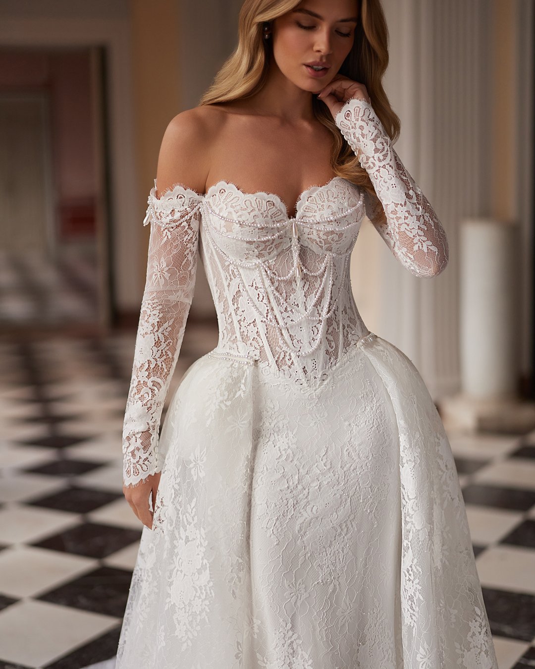 Suknia ślubna Sparkle z kolekcji AnnaSposa to ucieleśnienie nowoczesnej elegancji, łączące w sobie romantyzm długich rękawów i efektowny tren. Jej dopasowany krój w stylu tuby, ozdobiony francuską koronką i delikatnymi perłami, podkreśla sylwetkę, a przezroczysty gorset dodaje wyjątkowego szyku. Idealna dla panien młodych, które pragną w dniu swojego ślubu emanować blaskiem i pewnością siebie.