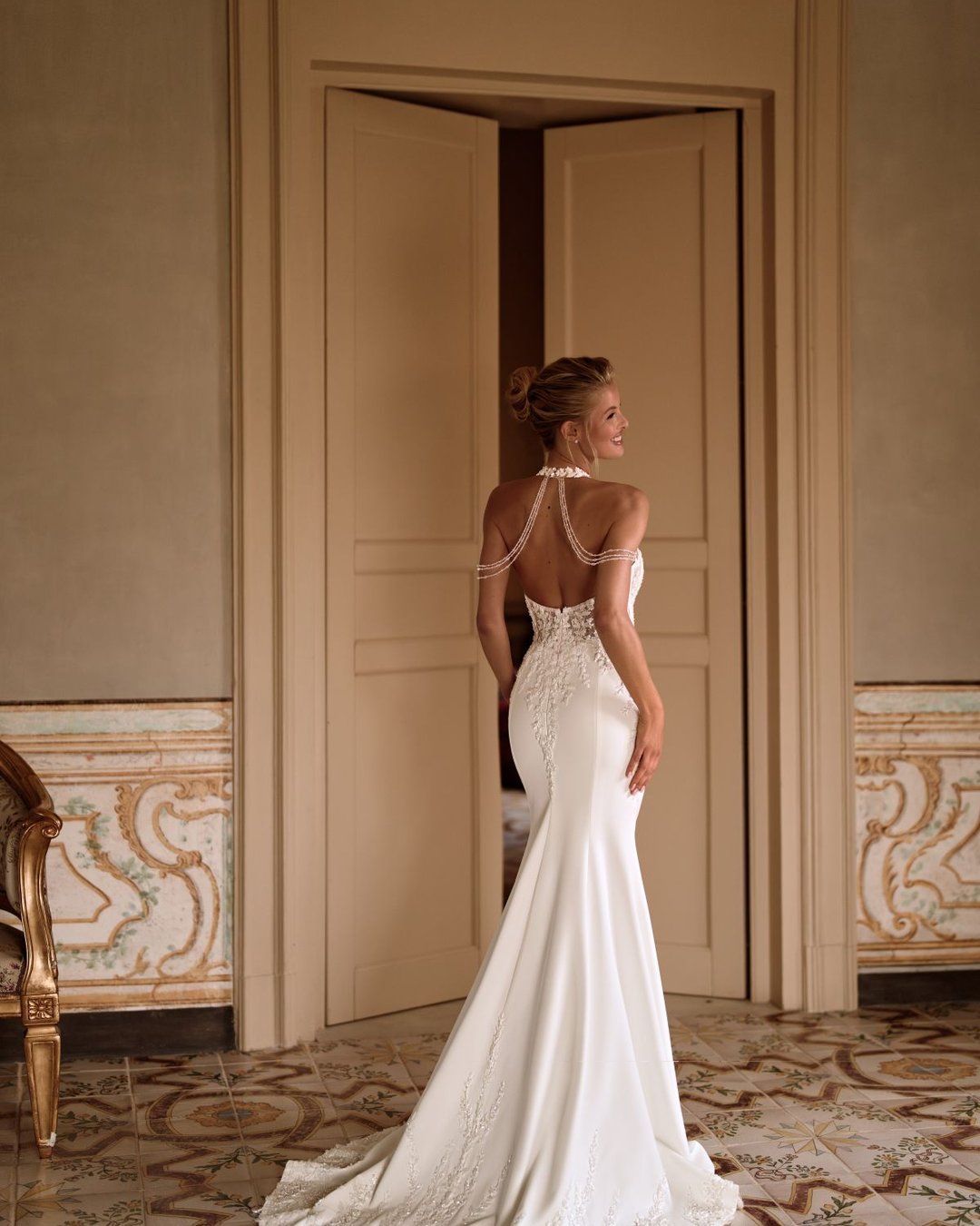 Suknia Sherwood to połączenie klasyki i nowoczesnej elegancji. Zmysłowy halter z opadającymi ramiączkami, przezroczysta koronkowa góra i gładka, wąska spódnica z trenem tworzą efektowną całość. Subtelne zdobienia nadają jej wyjątkowego blasku i lekkości.