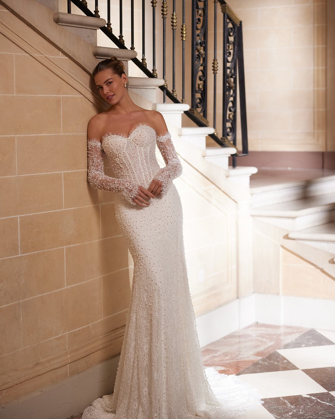 Suknia ślubna Amity z kolekcji AnnaSposa to kwintesencja elegancji i nowoczesności, która zachwyca dopasowanym krojem syrenki oraz zjawiskowym trenem. Wykonana z francuskiej koronki ozdobionej perłami, podkreśla kobiece kształty dzięki gorsetowemu fasonowi i efektownemu pasowi w kształcie litery V. Dodatkowy urok sukni nadaje wyjątkowy choker, który dopełnia całość, czyniąc każdą pannę młodą prawdziwą królową w dniu jej ślubu.