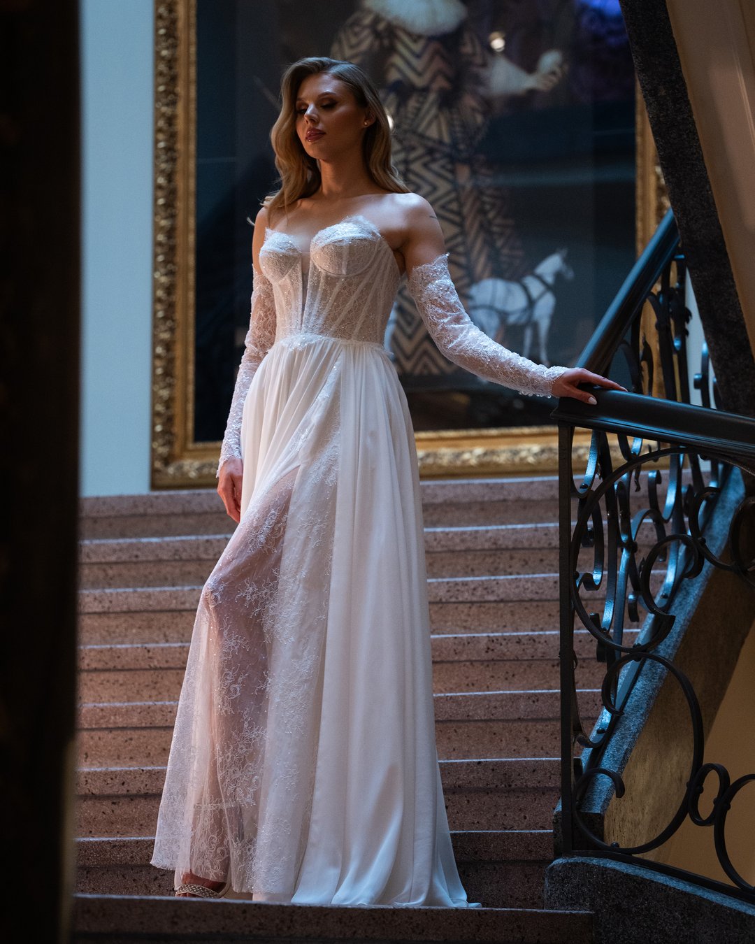 Suknia ślubna Viktoria z kolekcji LaLiven to kwintesencja boho elegancji, łącząca w sobie lekkość muslinu i subtelność francuskiej koronki. Dwuczęściowy fason z długimi rękawami, szeroką spódnicą oraz zmysłowym rozporkiem podkreśla sylwetkę, dodając wyjątkowego blasku każdej pannie młodej. Ta gorsetowa kreacja z pewnością sprawi, że Twój wyjątkowy dzień stanie się niezapomnianym przeżyciem.