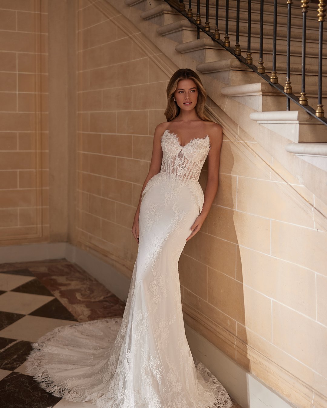 Suknia ślubna Vestira z kolekcji AnnaSposa to kwintesencja elegancji i klasyki, łącząca w sobie dwuczęściowy design z zjawiskowym trenem. Wykonana z delikatnego tiulu i francuskiej koronkowej tkaniny, ozdobiona perłami oraz przezroczystymi nakładanymi rękawami, podkreśla kobiece kształty dzięki gorsetowemu fasonowi i baskince. Idealna dla panien młodych pragnących olśniewać w dniu swojego ślubu.