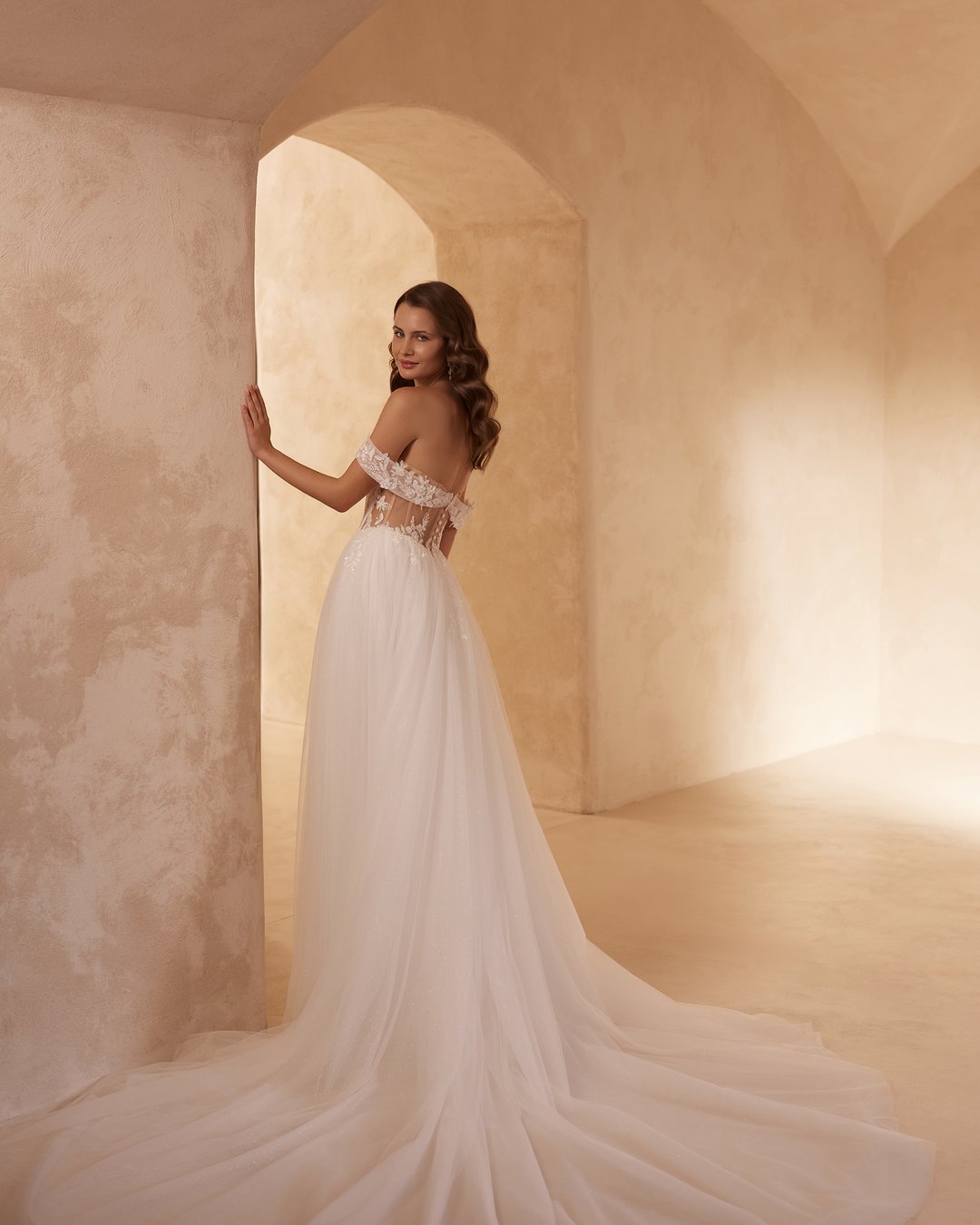 Suknia ślubna 5816 z kolekcji Elizabeth Passion to kwintesencja nowoczesnej elegancji, łącząca w sobie zmysłowość i delikatność. Jej szeroka spódnica z tiulu, ozdobiona koronkowymi detalami, doskonale współgra z gorsetowym topem i opadającymi ramiączkami, a subtelny rozporek dodaje całości odrobiny śmiałości. Pas w kształcie litery V podkreśla talię, tworząc sylwetkę, która oczaruje w tym wyjątkowym dniu.