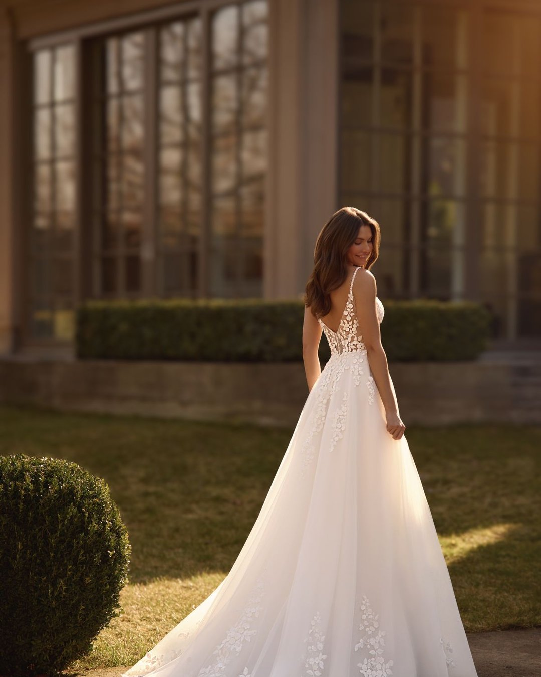 Suknia Obsidian to klasyczna i delikatna suknia ślubna o linii A, wykonana z tiulu ozdobionego subtelną koronką w kształcie drobnych kwiatków. Gorset z głębokim dekoltem w kształcie litery V oraz transparentnymi plecami nadaje sylwetce lekkości i romantyzmu. Suknia oparta na cienkich ramiączkach zdobionych perełkami pięknie eksponuje ramiona i szyję. Całość wieńczy lekki, delikatny tren, który płynnie dopełnia elegancki charakter sukni.