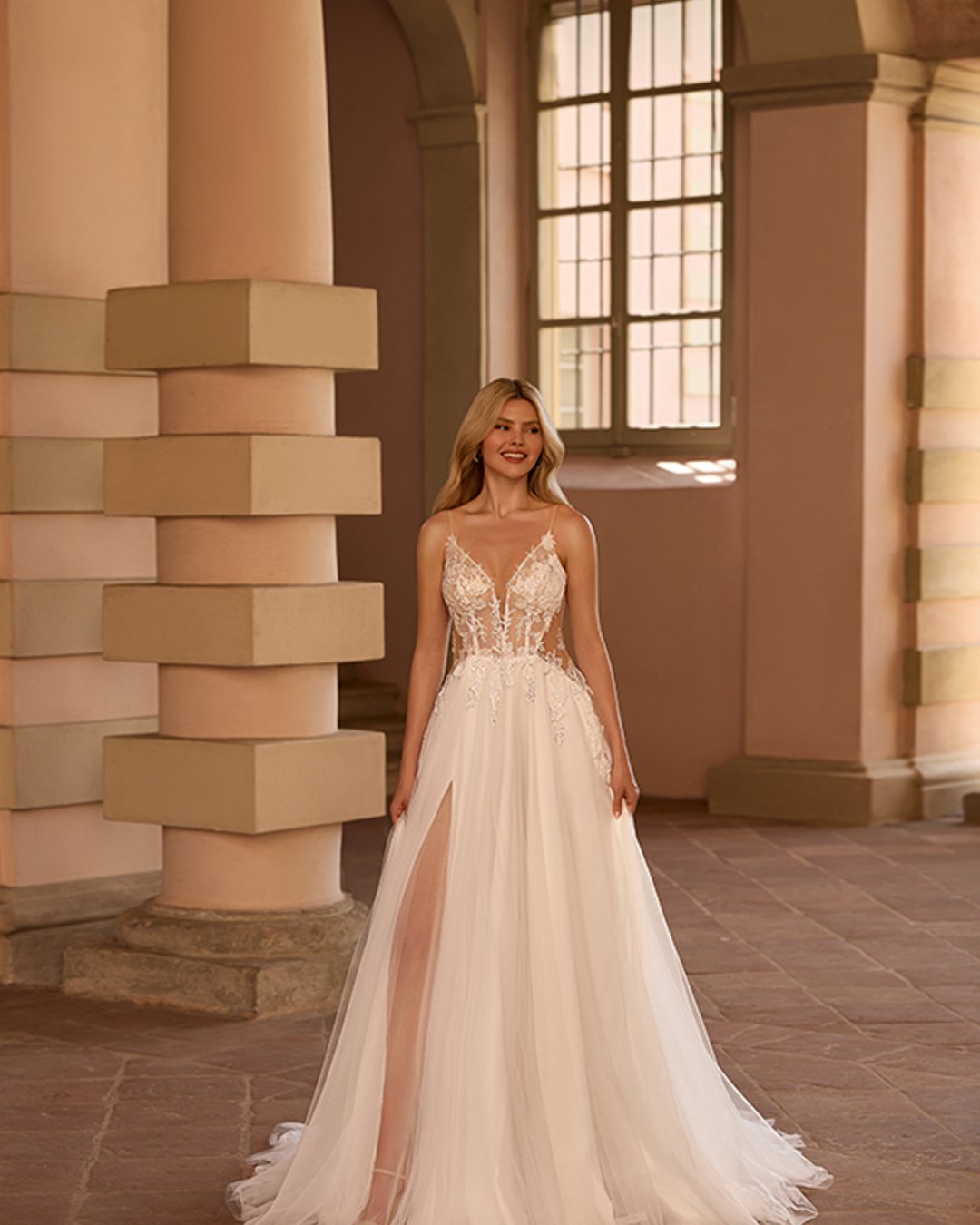 Model Setaria to delikatna i romantyczna suknia ślubna na cienkich ramiączkach, zachwycająca lekkością i kobiecym urokiem. Gorset z dekoltem w kształcie litery V oraz przezroczyste, błyszczące detale pięknie podkreślają sylwetkę, a szeroka, tiulowa spódnica w linii A nadaje kreacji zwiewności. Idealna propozycja dla Panny Młodej ceniącej klasyczną elegancję z nutą nowoczesności.