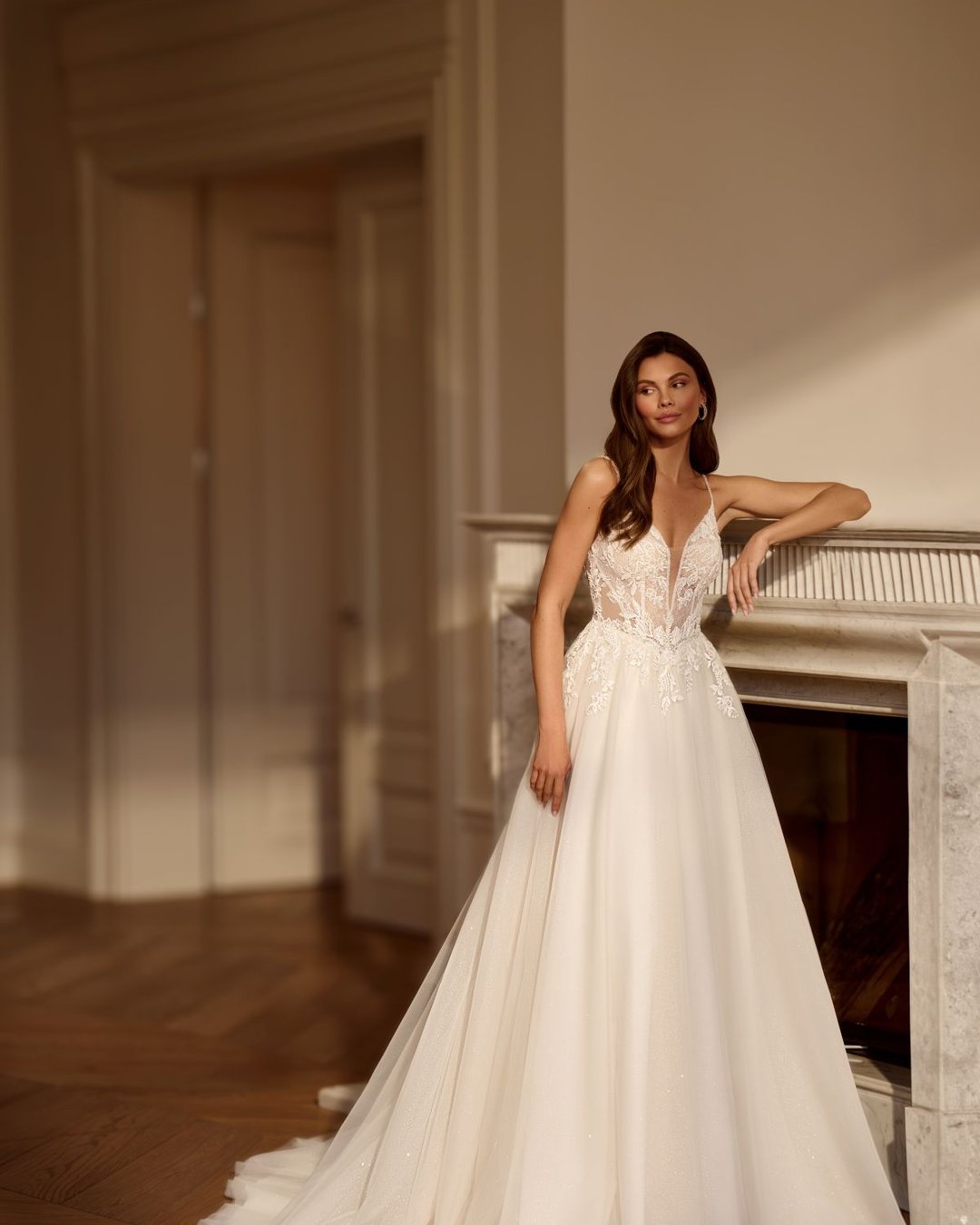 Zjawiskowa suknia w linii A na cienkich, delikatnych ramiączkach. Góra sukni wykonana z transparentnego tiulu zdobionego ręcznie wyszywaną koronką. Głęboki dekolt w kształcie litery V subtelnie eksponuje sylwetkę, a pięknie wycięte, koronkowe plecy dodają sukni romantyzmu i lekkości.