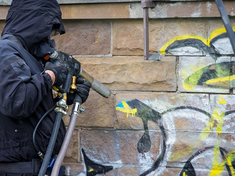 Removing graffiti with a wet sandblaster