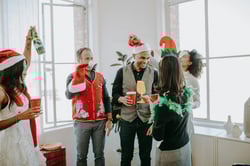 Colleagues celebrating a festive holiday party in an office settingenjoying drinks and wearing fun costumes.