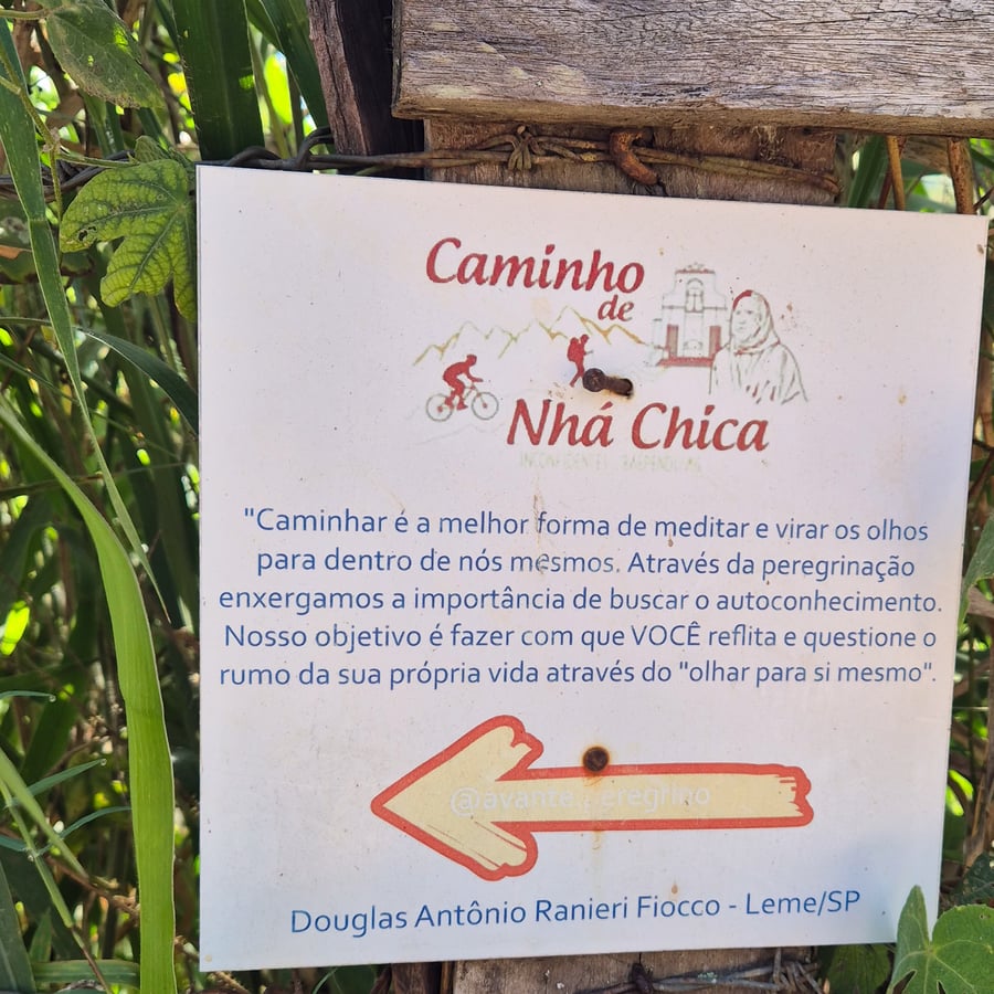 Placa do Caminho de Nhá Chica com frase sobre autoconhecimento e seta indicando a trilha