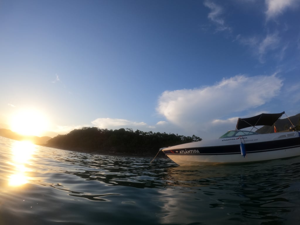 Pôr do sol visto do mar em Ubatuba durante passeio de lancha com paisagem dourada e clima tranquilo