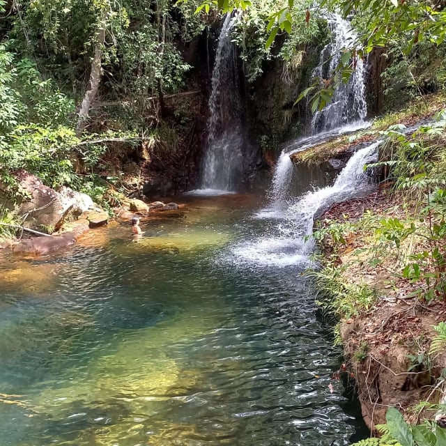 Cachoeira em cascata caindo sobre poço de águas verdes e cristalinas, cercado por mata