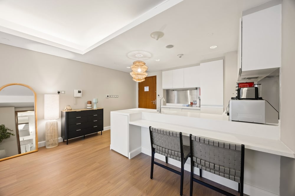 Studio living area with dresser, kitchen island and bar stools