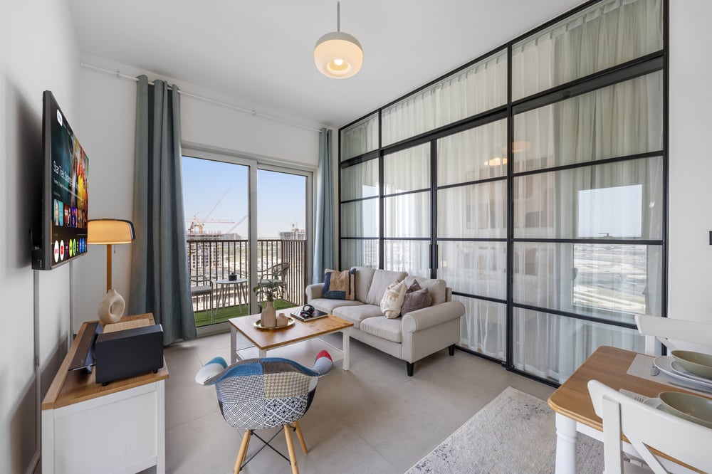 Living area with sofa, TV, glass partition, and balcony view