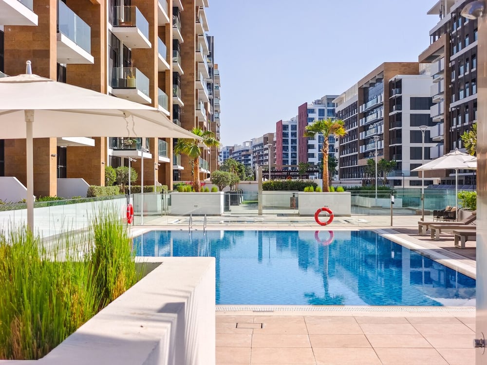 Outdoor swimming pool with sun loungers and apartment buildings