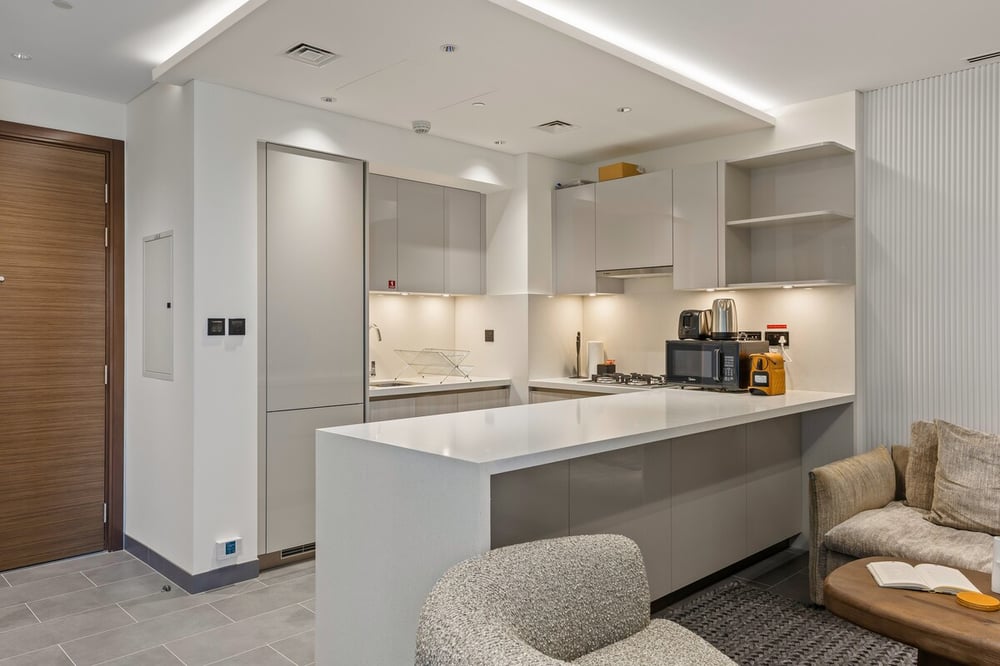 Kitchen peninsula with grey cabinets open to living room