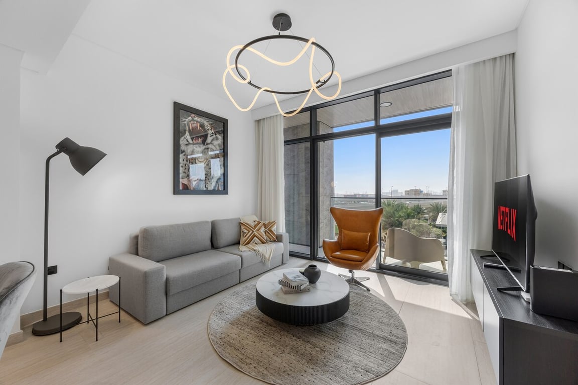 Living room with sofa, armchair, coffee table and city view balcony