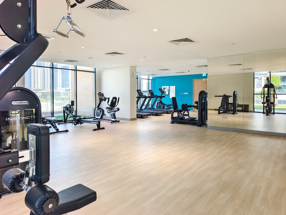 Building gym with various fitness machines and mirrors