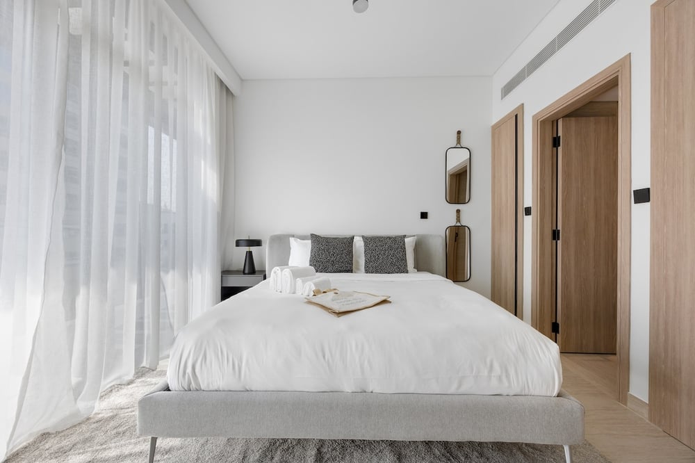 Bedroom with double bed, white linens and sheer curtains