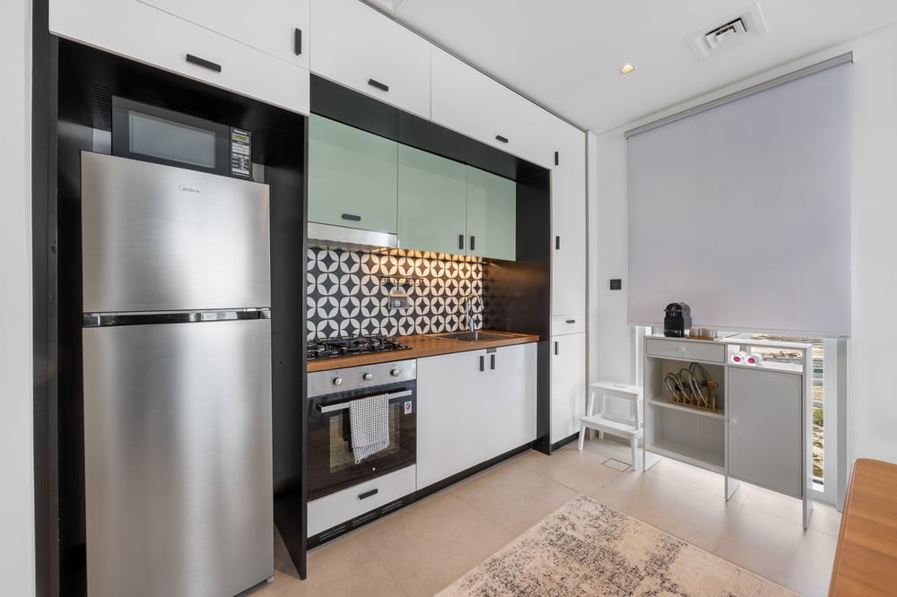 Compact kitchen with fridge, oven, and patterned tile backsplash